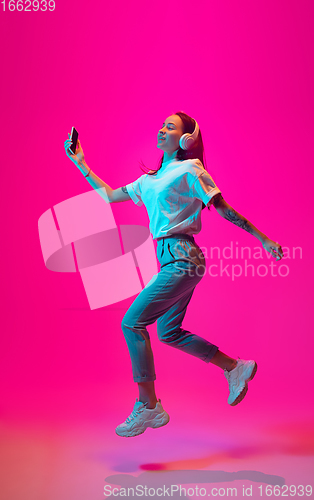 Image of Caucasian beautiful woman\'s portrait isolated on pink studio background in multicolored neon light