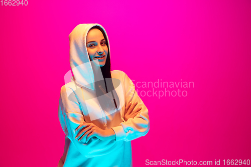 Image of Caucasian beautiful woman\'s portrait isolated on pink studio background in multicolored neon light