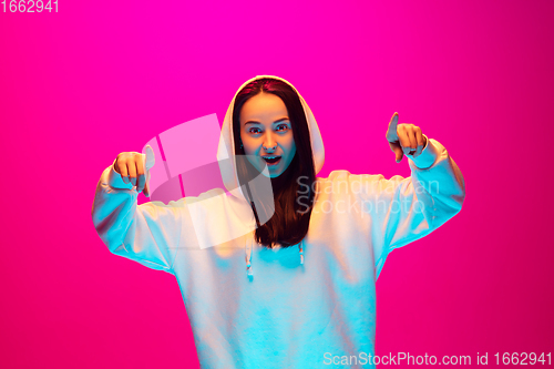 Image of Caucasian beautiful woman\'s portrait isolated on pink studio background in multicolored neon light