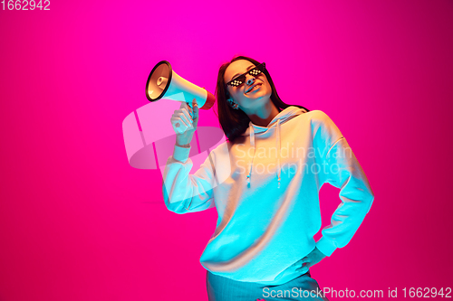 Image of Caucasian beautiful woman\'s portrait isolated on pink studio background in multicolored neon light