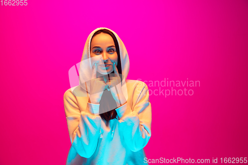 Image of Caucasian beautiful woman\'s portrait isolated on pink studio background in multicolored neon light