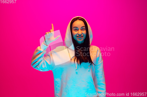 Image of Caucasian beautiful woman\'s portrait isolated on pink studio background in multicolored neon light