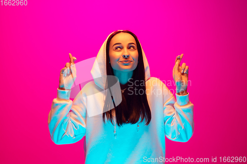 Image of Caucasian beautiful woman\'s portrait isolated on pink studio background in multicolored neon light