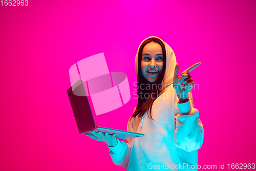 Image of Caucasian beautiful woman\'s portrait isolated on pink studio background in multicolored neon light