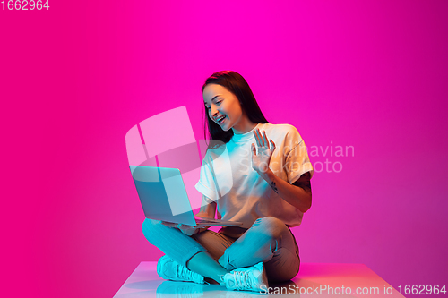 Image of Caucasian beautiful woman\'s portrait isolated on pink studio background in multicolored neon light