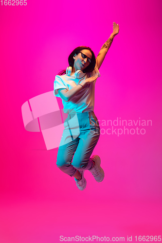 Image of Caucasian beautiful woman\'s portrait isolated on pink studio background in multicolored neon light