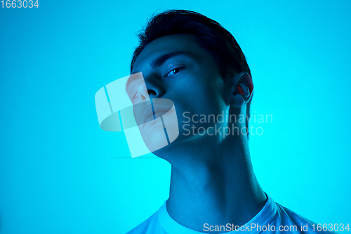 Image of Handsome caucasian man\'s portrait isolated on blue studio background in neon light, monochrome