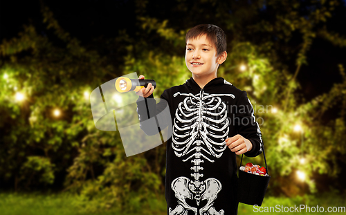 Image of boy in halloween costume with candies and torch