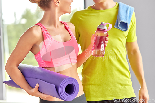 Image of couple with water bottle, mat and towel in gym