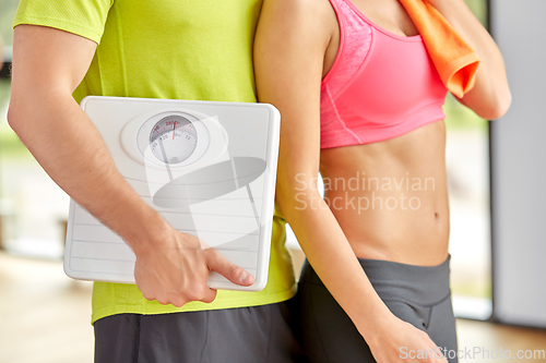 Image of close up of woman and man with scales in gym