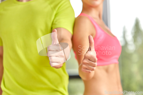 Image of close up of man and woman showing thumbs up in gym