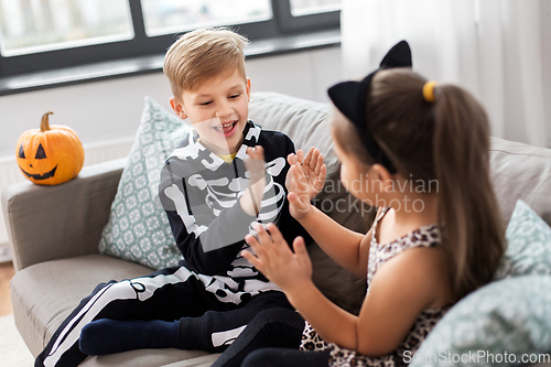 Image of kids in halloween costumes playing game at home