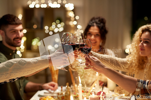 Image of happy friends drinking red wine at christmas party