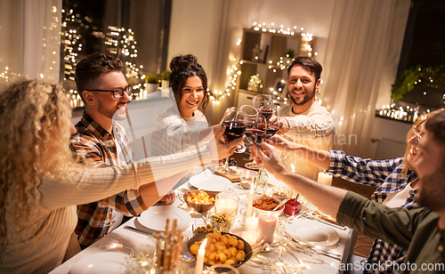 Image of happy friends drinking red wine at christmas party