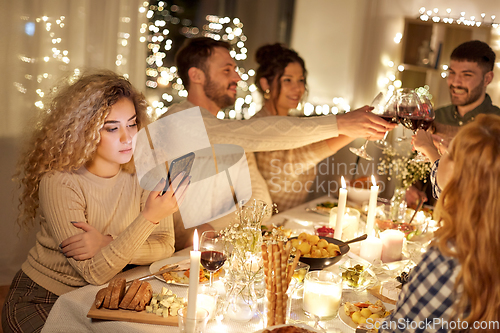 Image of woman with smartphone at dinner party with friends