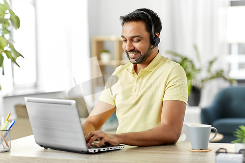 Image of indian man with headset and laptop working at home