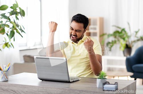 Image of happy man with laptop working at home office