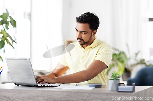 Image of man with laptop and papers working at home