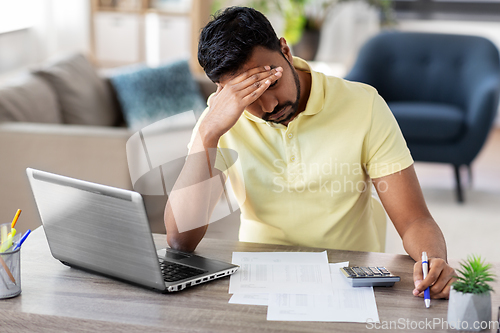 Image of man with calculator and papers working at home