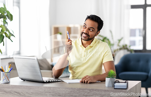 Image of indian man with notebook and laptop at home office