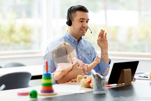 Image of father in headset working at home office with baby