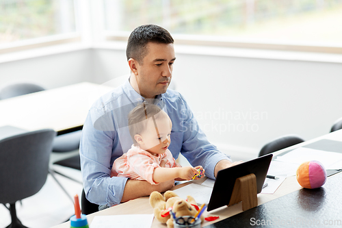 Image of father with baby working on tablet pc at home