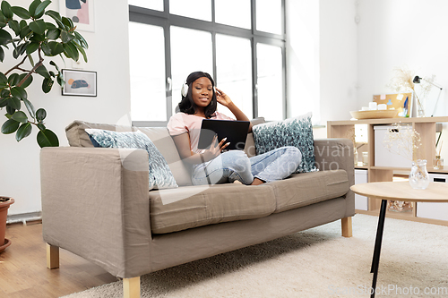 Image of woman with tablet pc listening to music at home