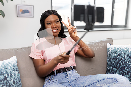 Image of happy african american woman taking selfie at home