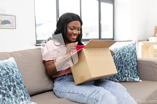Image of african american woman opening parcel box at home
