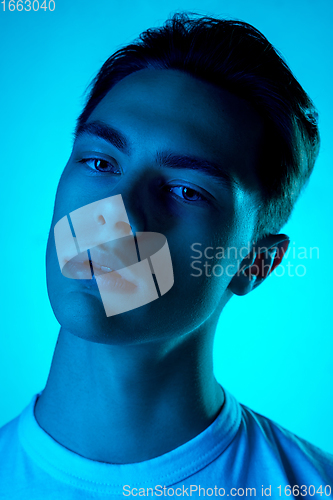 Image of Handsome caucasian man\'s portrait isolated on blue studio background in neon light, monochrome