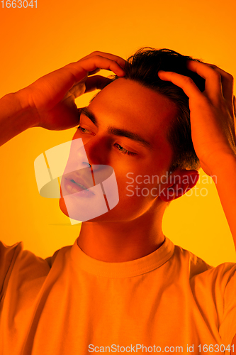 Image of Handsome caucasian man\'s portrait isolated on orange studio background in neon light, monochrome