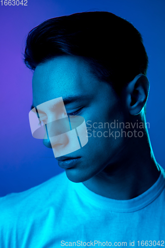 Image of Handsome caucasian man\'s portrait isolated on purple studio background in neon light, monochrome