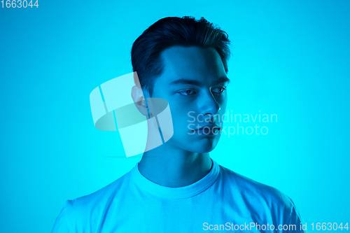 Image of Handsome caucasian man\'s portrait isolated on blue studio background in neon light, monochrome