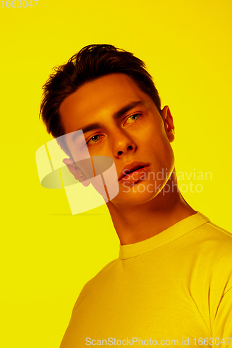 Image of Handsome caucasian man\'s portrait isolated on orange studio background in neon light, monochrome