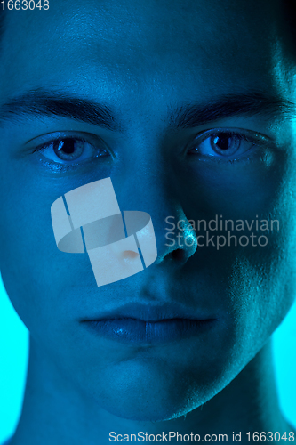 Image of Handsome caucasian man\'s portrait isolated on blue studio background in neon light, monochrome