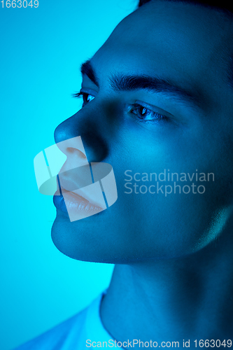 Image of Handsome caucasian man\'s portrait isolated on blue studio background in neon light, monochrome