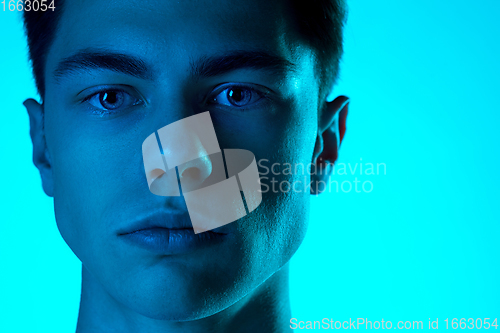 Image of Handsome caucasian man\'s portrait isolated on blue studio background in neon light, monochrome