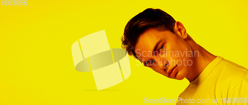 Image of Handsome caucasian man\'s portrait isolated on orange studio background in neon light, monochrome