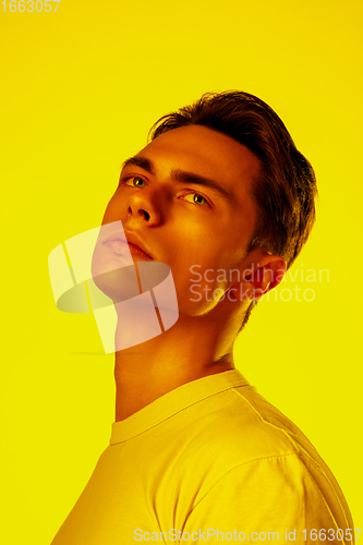 Image of Handsome caucasian man\'s portrait isolated on orange studio background in neon light, monochrome