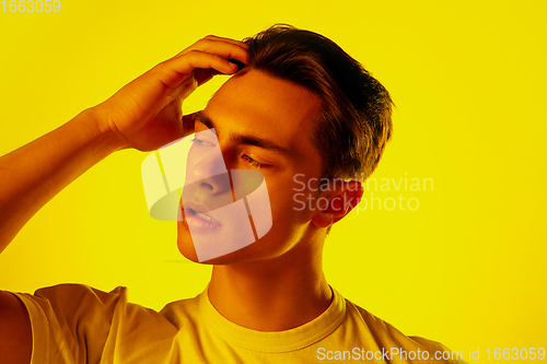 Image of Handsome caucasian man\'s portrait isolated on orange studio background in neon light, monochrome