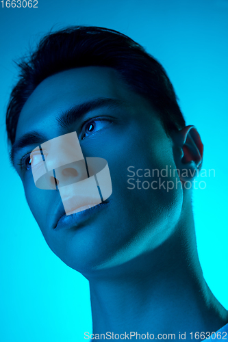 Image of Handsome caucasian man\'s portrait isolated on blue studio background in neon light, monochrome