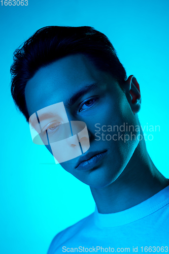 Image of Handsome caucasian man\'s portrait isolated on blue studio background in neon light, monochrome