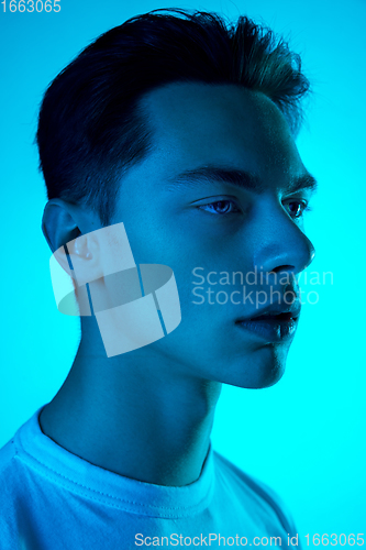 Image of Handsome caucasian man\'s portrait isolated on blue studio background in neon light, monochrome