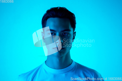 Image of Handsome caucasian man\'s portrait isolated on blue studio background in neon light, monochrome