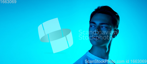 Image of Handsome caucasian man\'s portrait isolated on blue studio background in neon light, monochrome