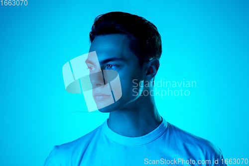 Image of Handsome caucasian man\'s portrait isolated on blue studio background in neon light, monochrome