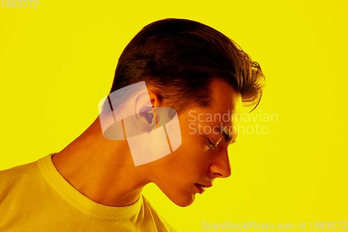 Image of Handsome caucasian man\'s portrait isolated on orange studio background in neon light, monochrome