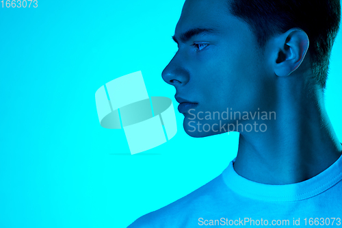 Image of Handsome caucasian man\'s portrait isolated on blue studio background in neon light, monochrome