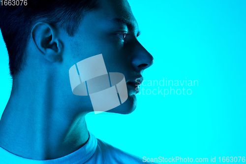 Image of Handsome caucasian man\'s portrait isolated on blue studio background in neon light, monochrome