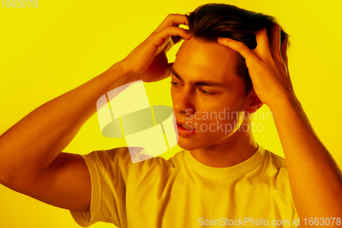 Image of Handsome caucasian man\'s portrait isolated on orange studio background in neon light, monochrome